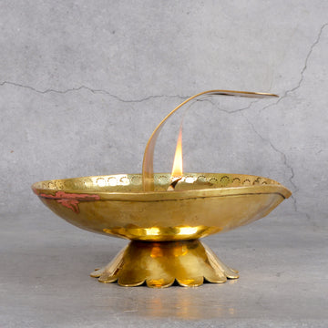 Brass incense burner with flame on a gray background